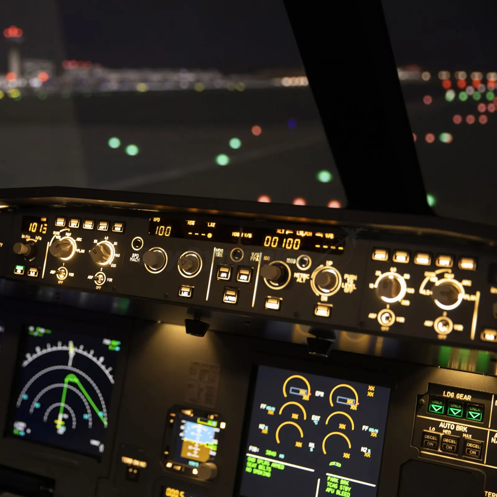 Flight control unit and displays of the SkyDynamics A320 simulator at night, with runway lights ahead