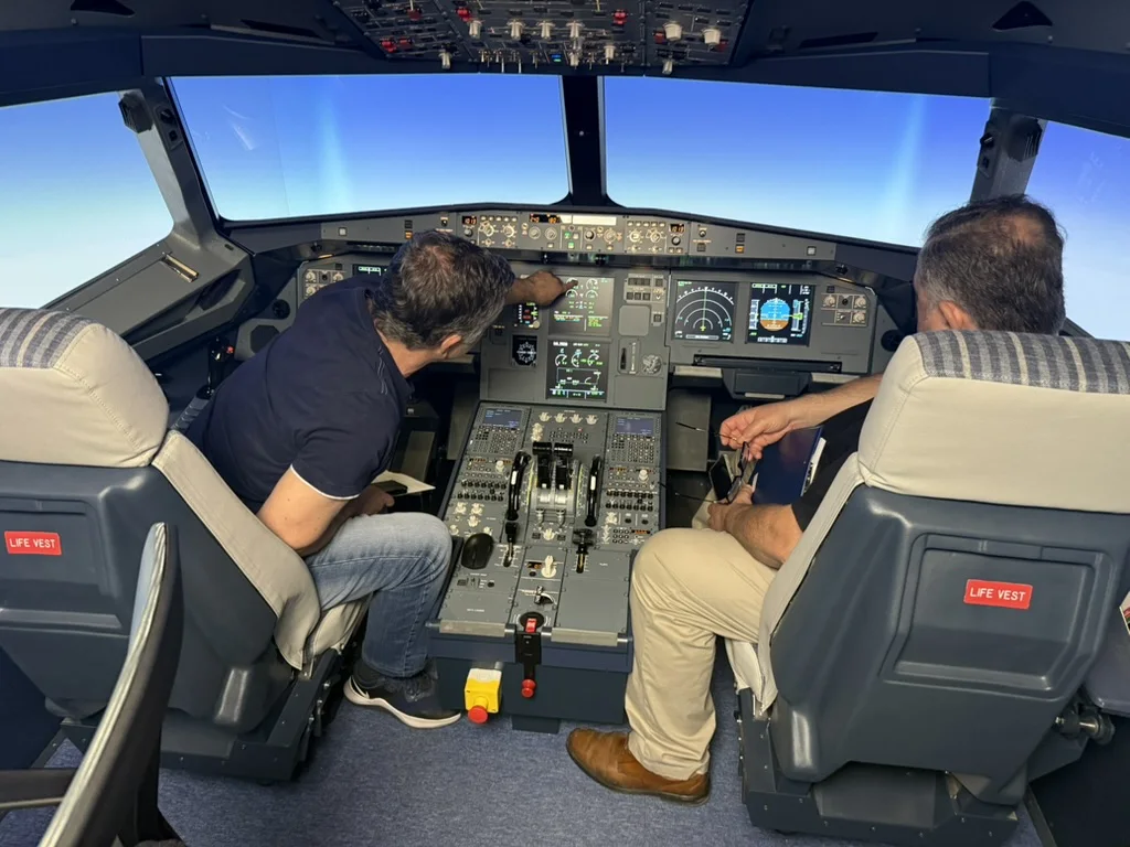 Two team members checking the displays on the flight deck of the A320 FNPT II simulator
