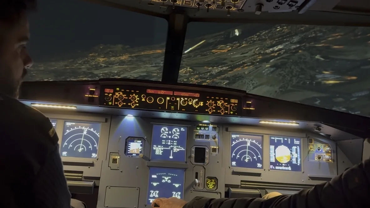 Crew flying the A320 simulator at night over a lit city