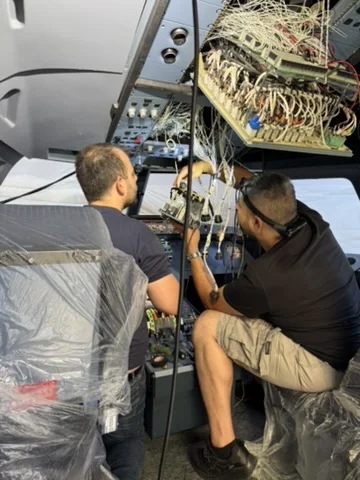 Two engineers working on the overhead panel wiring of the A320 simulator